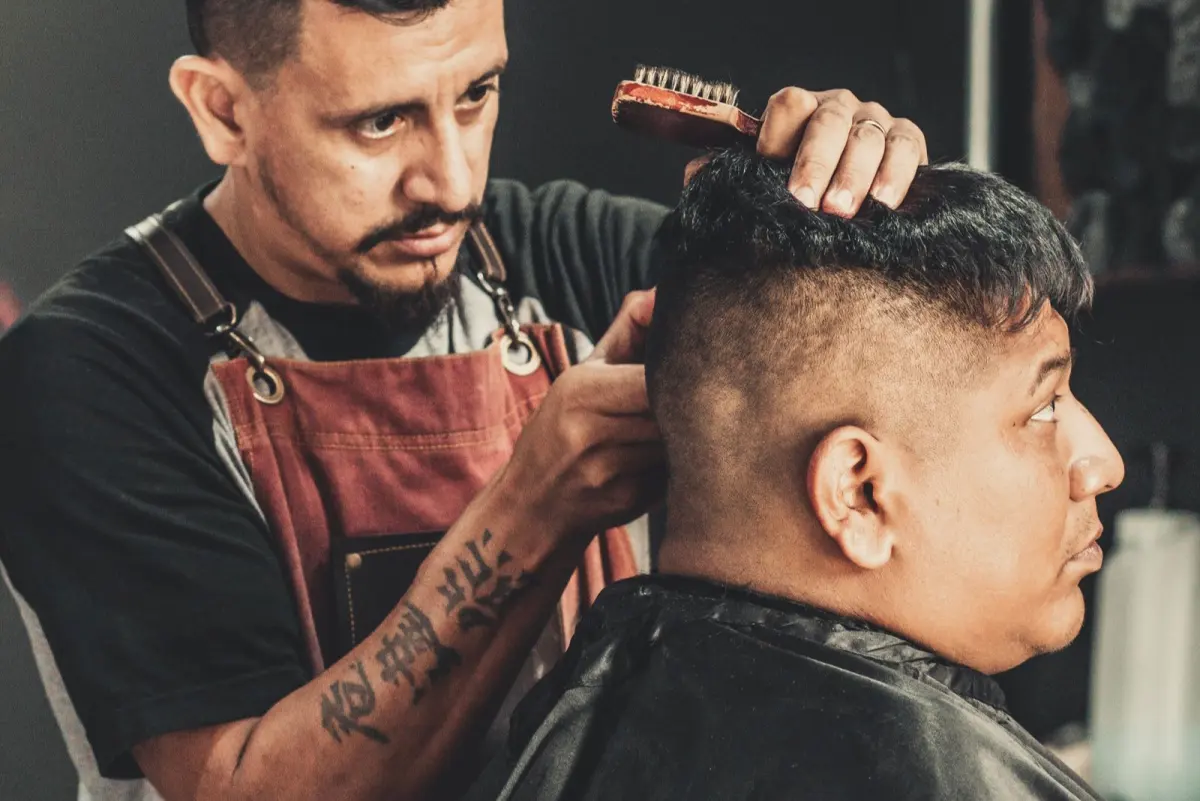 A barber finishing a cut in a lit shop